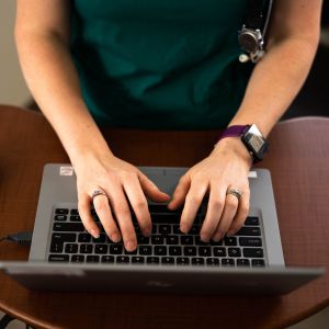 a health worker's hands above a keyboard