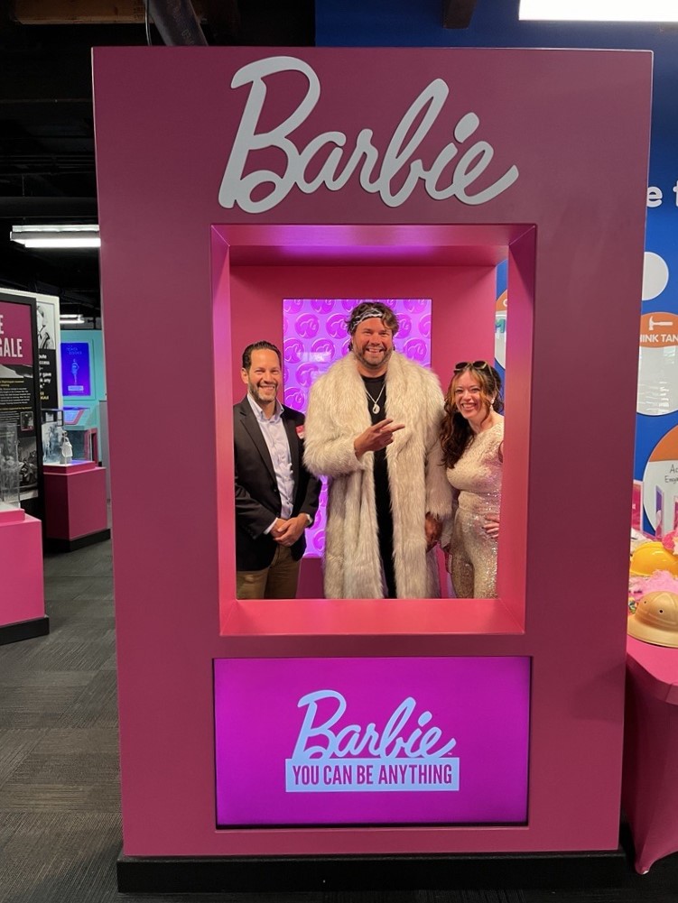 MSU Health Care CEO Seth Ciabotti, MSU Health Care Surgery clinic manager Erik Flowers, and MSU Health Care marketing project manager Lindsay Gulf-Magar posing in a Barbie box